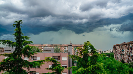 Fototapeta na wymiar Heavy storm with dark clouds over residential buildings in Milan, Italy.