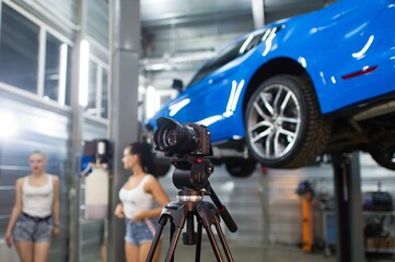 DSLR camera on tripod during commercial production, unfocus young women and car on background