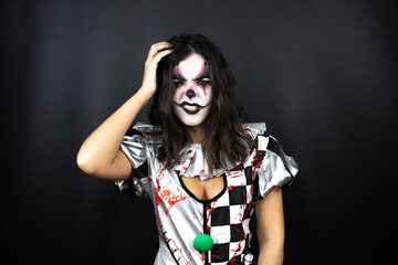 woman in a halloween clown costume over isolated black background confuse and wonder about question. Uncertain with doubt, thinking with hand on head