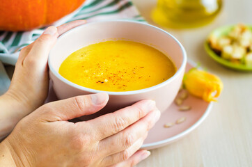 Woman hands with bowl of tasty creamy pumpkin soup with seeds and croutons, closeup.  Thanksgiving Day. traditional autumn dish. soft focus