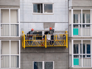 construction workers installers high-rise workers industrial climbers, painters on the lift paint...