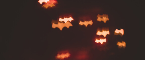 defocused bokeh gold lights in shape of bats for halloween background - holidays, decoration and party concept. banner