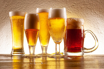 .Various types of beers served in glasses and crystal mugs on rustic wooden table
