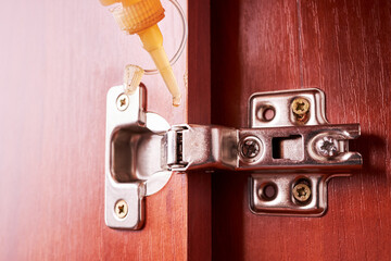 repairman using oil to grease furniture hinge. furniture adjustment. real life. person repair cabinet loop