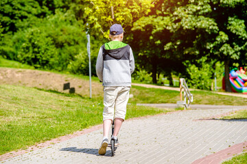 Fototapeta premium A boy rides a scooter in a city Park