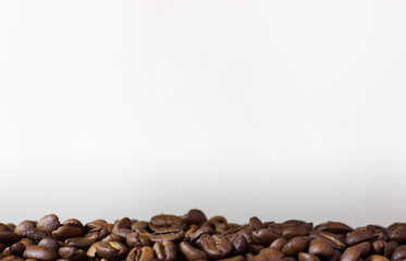 Roasted coffee beans on white background. Heap of coffee beans. Poured coffee close up. White pattern with coffee beans. Template with coffe on white background