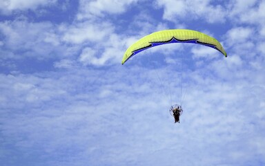 Paraglider at the seaside against the blue, slightly cloudy sky.