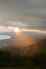 View from the mountains to the sunset in the resort town of Gelendzhik. September 2020.Black Sea, part of the bay. The sun's rays fall on the mountains.