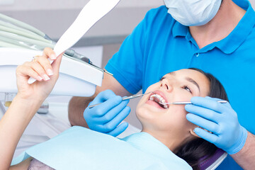 Naklejka premium Attractive young woman in a dental clinic with a male dentist. Healthy teeth concept.