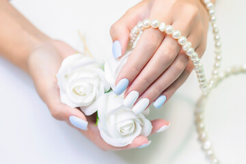 Stylish fashionable female manicure. Beautiful hands of a young woman on a background of flowers and beads from pearls