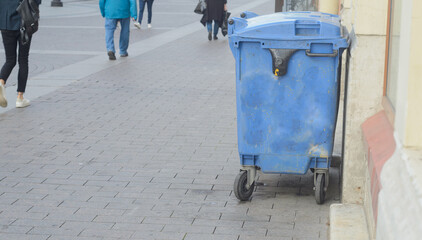 Closed blue trash can at the wall of the house on the street, copyspace