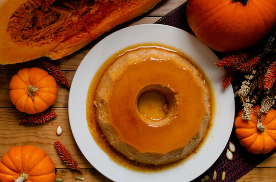 Pumpkin flan, dessert made for the Day of the Dead. Dessert on wooden table with autumn decoration around.