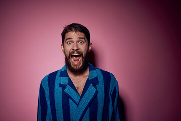 Fototapeta premium Bearded man in a blue striped robe on a pink background with hands emotions model portrait