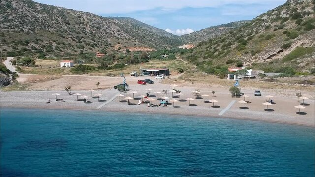 Chios Island Greece, a secluded sandy beach on the island, blue sea with umbrellas, located between hills