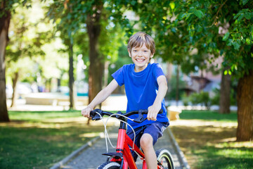 Happy young boy riding a bicycle in park