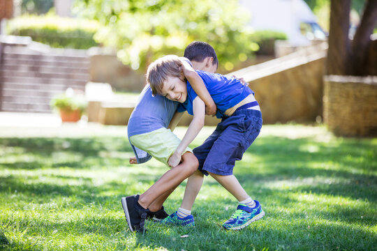 Two boys fighting outdoors. Siblings or friends wrestling in park.
