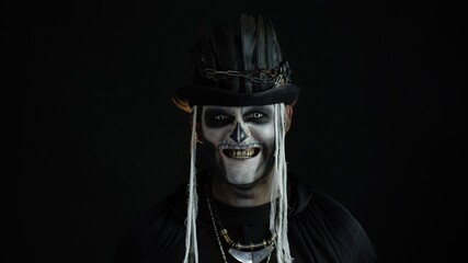Creepy man with skeleton makeup in top-hat. Guy making faces, toothy smile. Halloween thematic party
