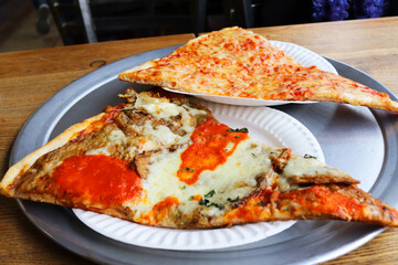 Two slices of New York thin crust pizza, one plain mozzarella cheese, the other mozzarella cheese,...