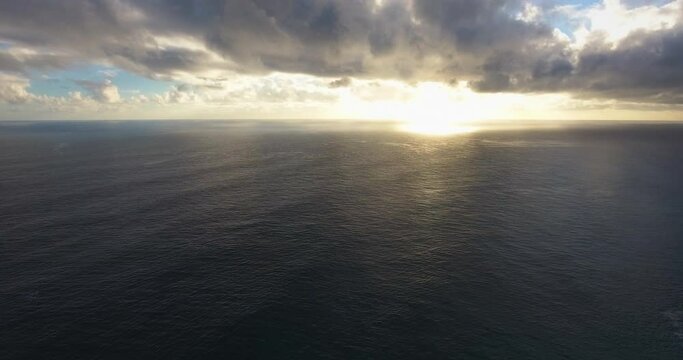 Wide aerial, sun sets over ocean horizon in Hawaii