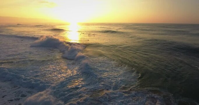 Wide aerial, surfers in Hawaii at sunset