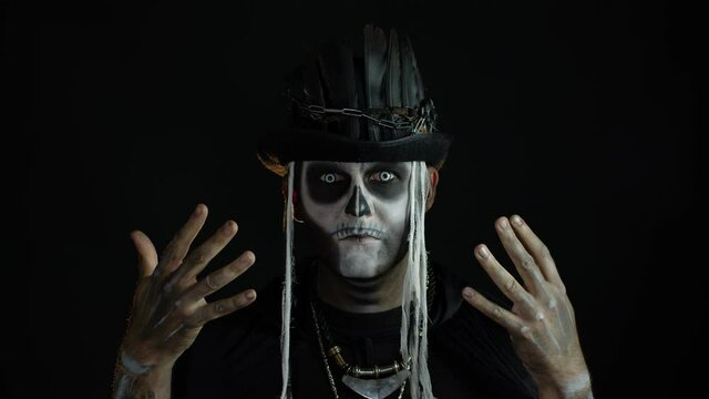Scary guy in carnival costume of Halloween skeleton against black background. Man skull makeup