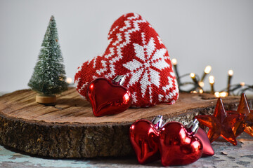 Christmas decoration: handmade hearts of fabric and knitting, stars, toys, Christmas tree and light on the rustic table with gray background.