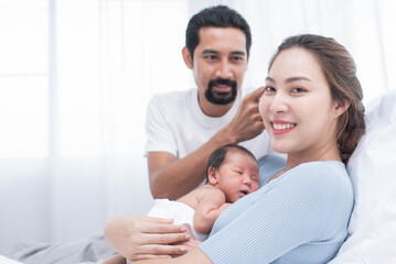 smiling mother and father holding their newborn baby at home..portrait of happy family at home, young parents holding on hands little sweet newborn baby, love and happiness concept.