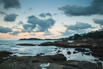 Fototapeta premium Peaceful landscape of a dreamy sunset at Bombinhas beach, Brazil, with the seawater on a silk effect and cottony clouds in the sky.