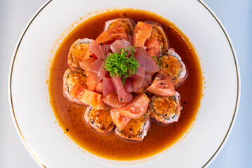 Overhead view of ahi tuna stacked upon California roll and tomatoes delicately presented on a plate to eat