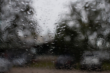 Bright water on the car window, after rain evening, in the parking, take closeup photography, color black and gray background blurred and landscape.
