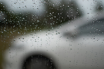 Raindrops on car windows evening after work in the parking, closeup photography, background with white cars blurred and the picture is horizontal and beautiful.