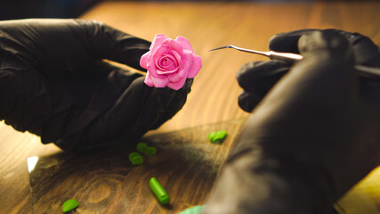 Creation of polymer clay flower. Craftsman at job, soft selective focus.