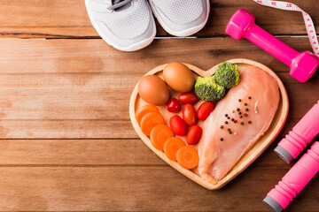 Top view of Raw chicken breasts fillets no boneless with spices in heart plate wood and sport or athlete's equipment dumbbell.running shoes on wooden background, Healthy lifestyle diet food concept