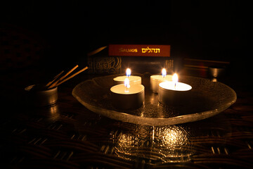 Candles lit on the day of Yom Kippur with the book of Psalms and the Bible in the background. - obrazy, fototapety, plakaty
