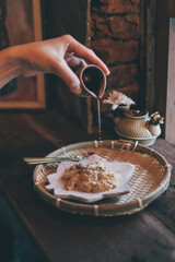 Hand pouring Brown Sugar Syrup into Warabi-mochi or Kinako mochi, bracken-starch dumpling on vintage background. Japanese Traditional dessert.