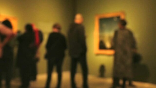View of people walking during an art gallery exhibition visit. Background with an intentional blur effect applie. 4K