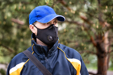 A man wearing respirator mask and a cap outdoors.