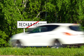 road sign end of town Lesnaya Polyana or Forest Glade, a satellite city of Kemerovo, green forest, grass and white avto
