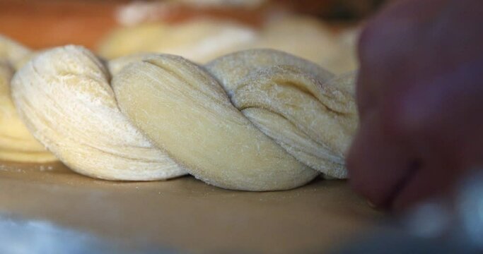 Low Angle Close Up On Hands Tying Dough Together To Make Challah For Thanksgiving.