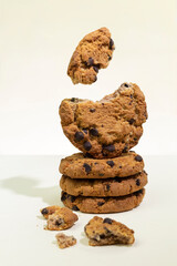 Chocolate chip cookies on light beige background. Broken cookies with pieces levitate.