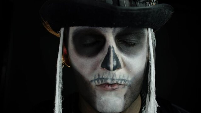 Man in skeleton Halloween cosplay costume. Guy in creepy skull makeup looking wide open eyes