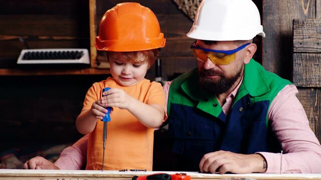 Construction of father and son in the garage. Little son helping his father with building work.