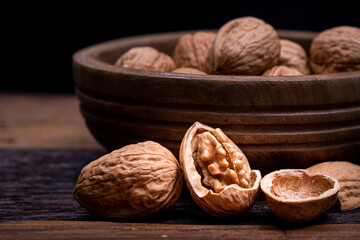 still life with Walnut kernels and whole walnuts on rustic old wooden table.