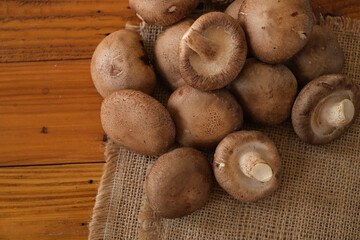 Raw Chinese mushroom or Shitake mushroom on the sackcloth over wooden table background. Selective focus.
