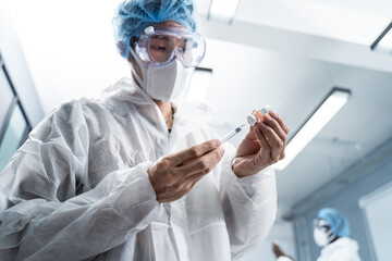 Asian young male doctor wearing white gown, holding hypodermic syringe