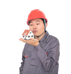 Worker in red hard hat kisses small house model in hand