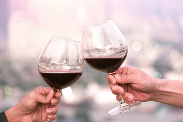 Hand of a lover's dinner is celebrated with red wine at a restaurant in a romantic atmosphere. Sunset and modern city background