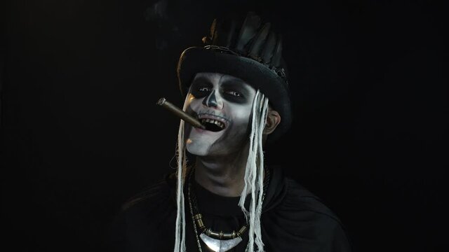 Frightening man in skeleton Halloween cosplay costume smoking cigar, making faces, smiling