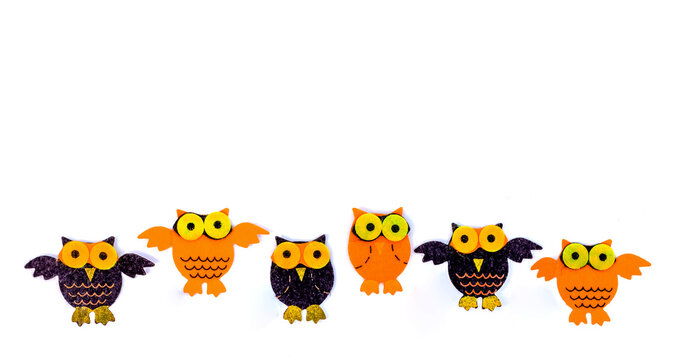 Children's hand-crafted application. Stuffed felt owl isolated on white background with empty space for text. Owls stitched from orange and black felt. Cute felt toy background.