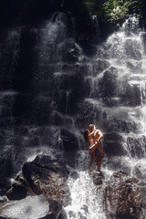 Couple under waterfall. People on vacation. Bali theme.